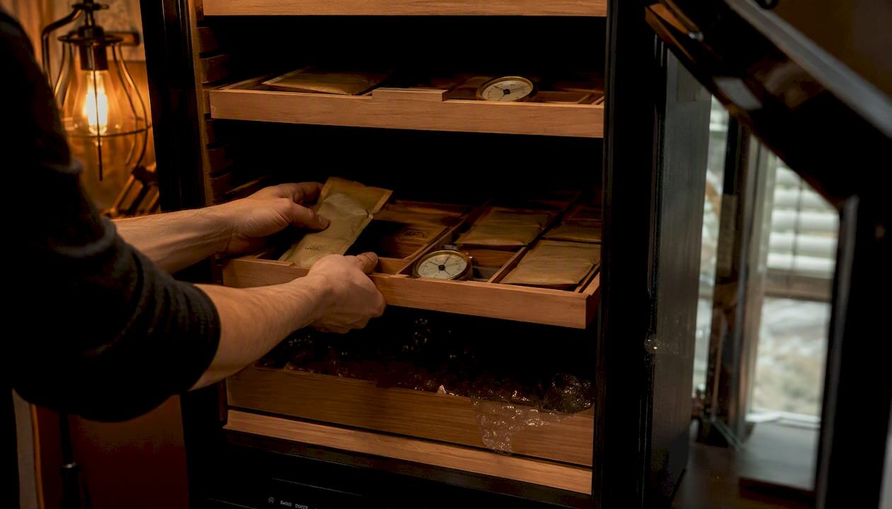 Hands placing Boveda packs and hygrometers on cedar trays
