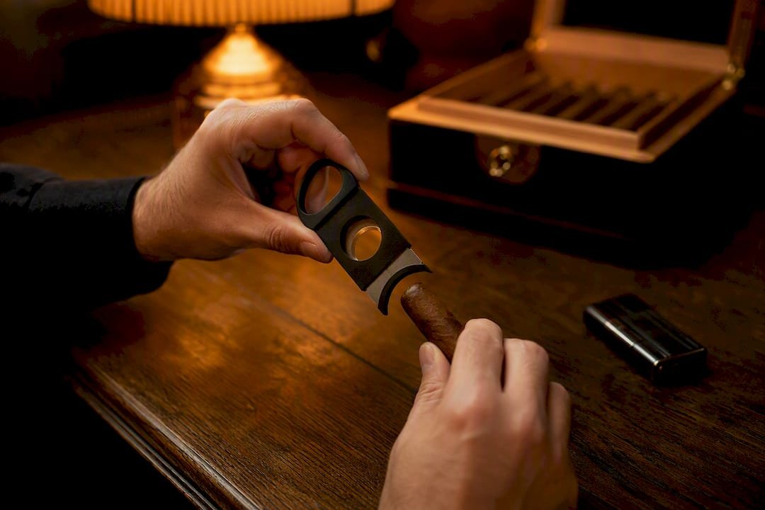 Hand holding cigar cutter preparing to cut