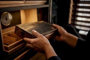 Hands removing sealed cigar box from humidor