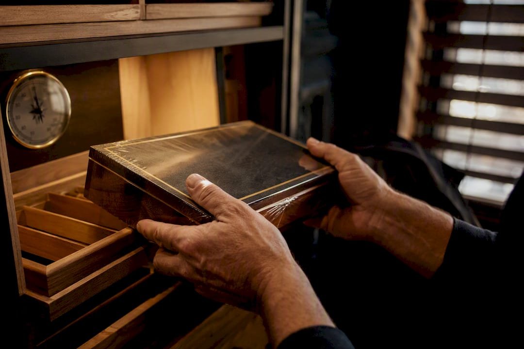 Hands removing sealed cigar box from humidor