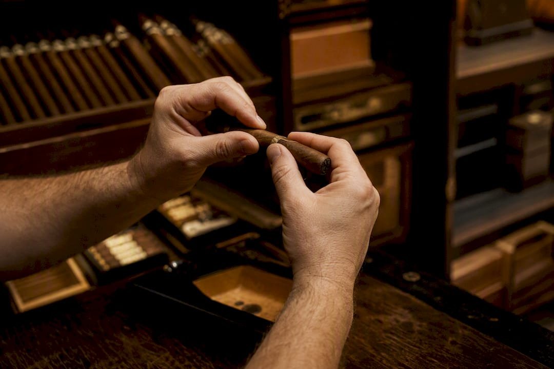 Tobacconist hands testing cigar draw in vault