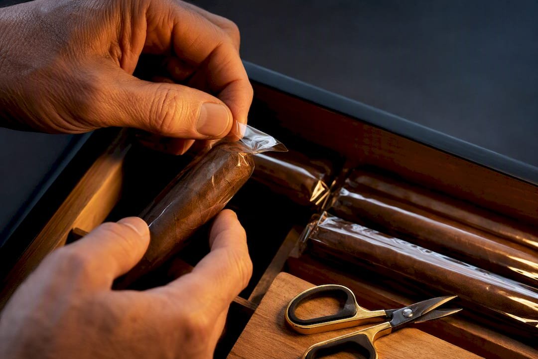 Hands partially opening cigar cellophane sleeve