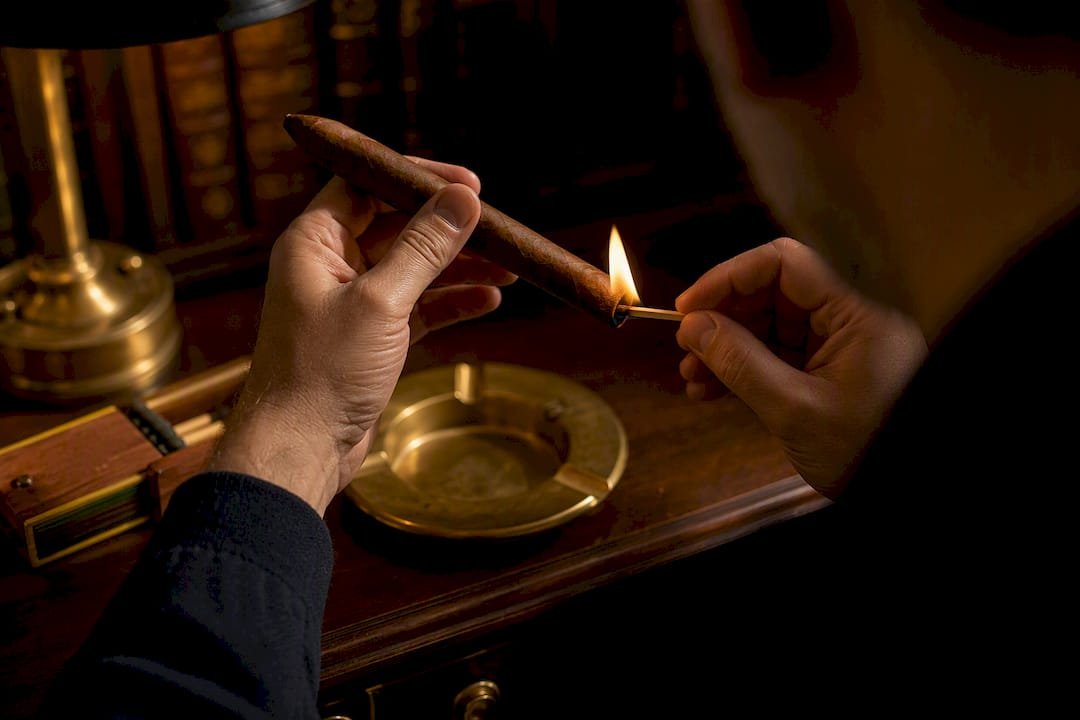 Hands rotating Perfecto cigar while lighting